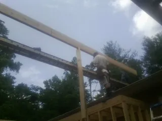 Carpenter setting a ridge beam over a new addition frame — Ice Dam Removal by Roofing Brothers in Perryman