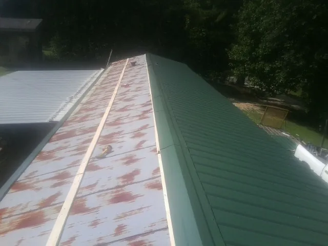 Old rusted panels beside newly installed green metal roofing — Wind Damage Roof Repair by Roofing Brothers in Perryman