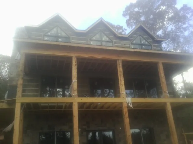 Dormers and porch framing on a large log home under construction — Roof Coating work by our crew in Perryman