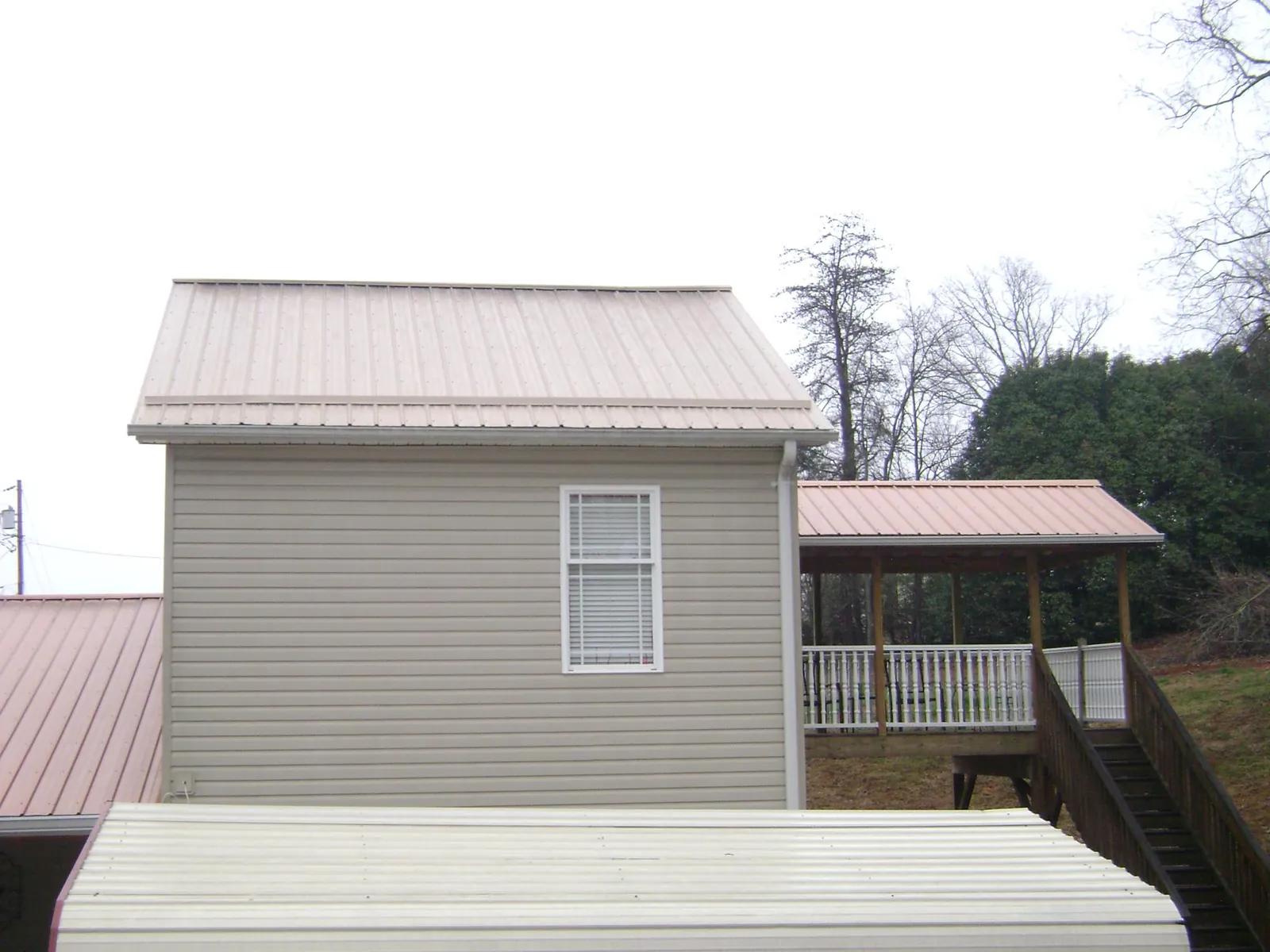 Tan metal roofs on a two story addition and attached porch, from a Roof Replacement job in Perryman
